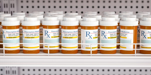 Row of prescription bottles on pharmacy shelf
