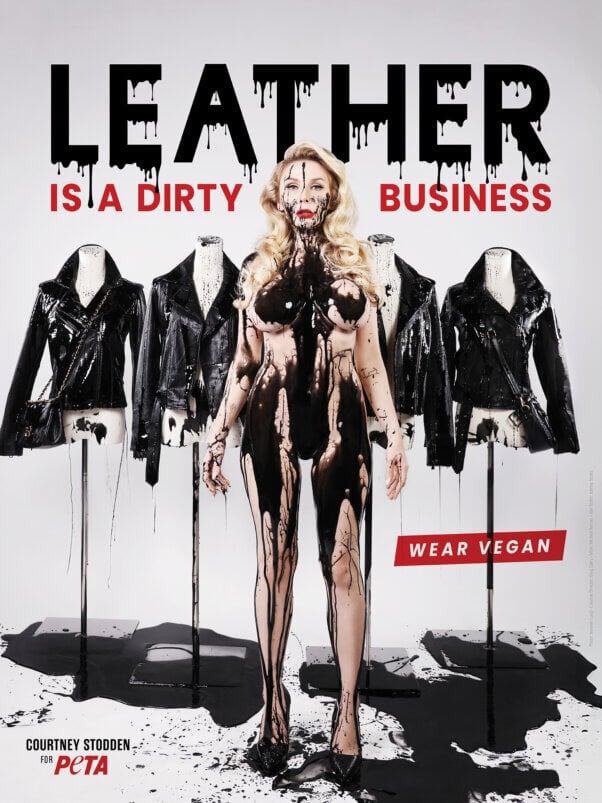 Model Courtney Stodden stands nude but covered in black sludge in front of mannequins wearing leather jackets. Text on the image reads: “Leather Is a Dirty Business. Wear Vegan.”
